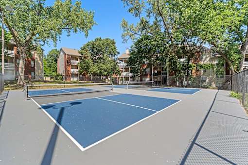 A tennis court surrounded by trees and buildings.