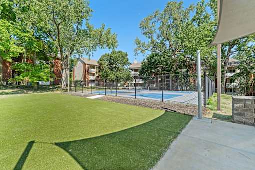 A sunny day at a residential area with a green lawn and a pool.