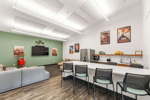A room with a grey couch, a white counter, and a TV on the wall.