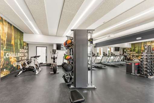 A gym with a variety of equipment including treadmills, weights, and exercise bikes.