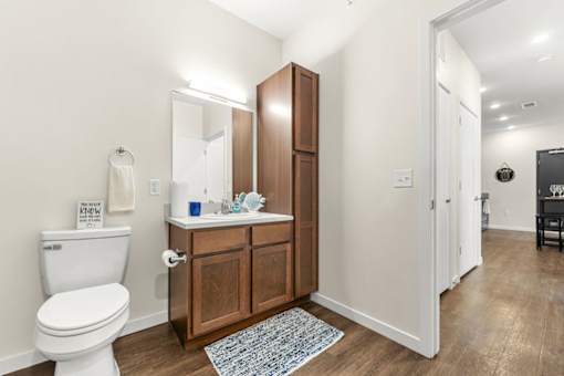 A bathroom with a toilet, sink, and wooden cabinet.