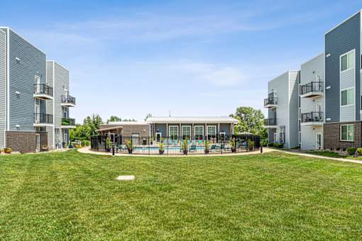 A grassy area in front of apartment buildings with a playground.