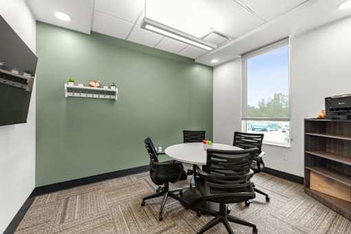 A conference room with a white table and four chairs.