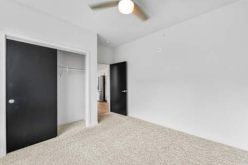 A room with a carpeted floor and two black doors.