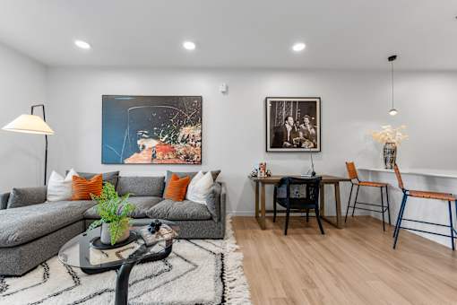 A living room with a grey couch, a coffee table, and a painting on the wall.