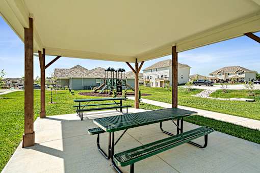 A green picnic table is under a white canopy.