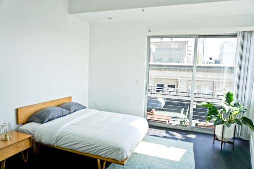 A bedroom with a bed, a chair, and a potted plant.