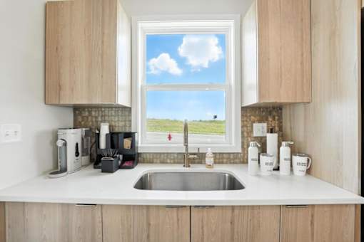 A kitchen with a window overlooking a field.