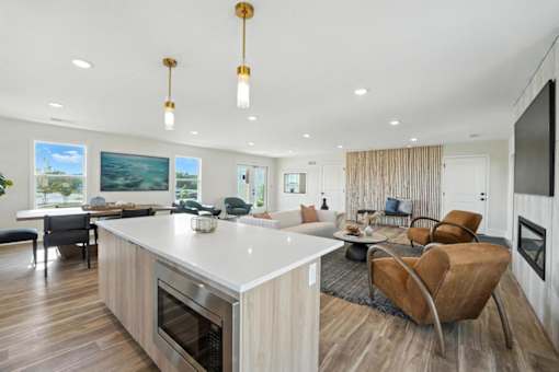 A modern kitchen with a large island and a dining area with chairs.