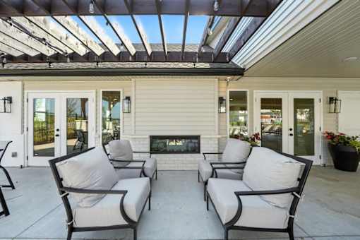 A patio with four chairs and a fireplace.