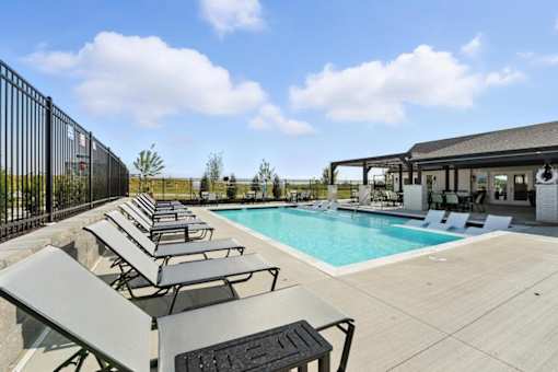 A pool area with sun loungers and a black fence.