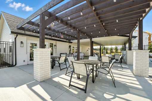 A patio with a table and chairs under a wooden pergola.