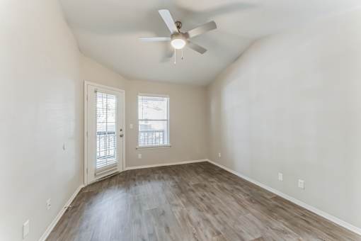 A room with a ceiling fan and wooden flooring.
