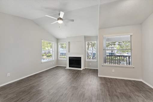 A spacious living room with a fireplace and a ceiling fan.