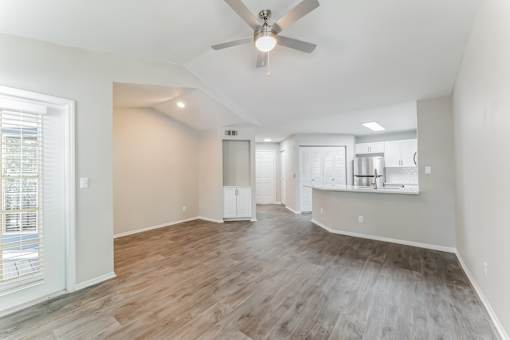 A spacious room with a ceiling fan and wooden flooring.