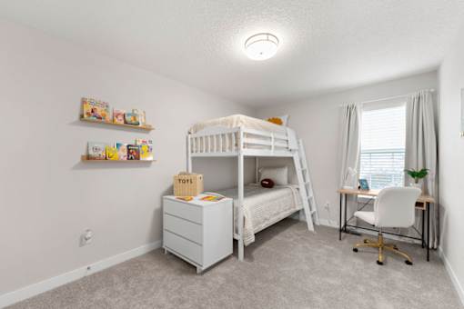 A white bunk bed with a desk and chair in a room.