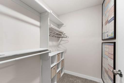 A white closet with a white shelf and a white door.
