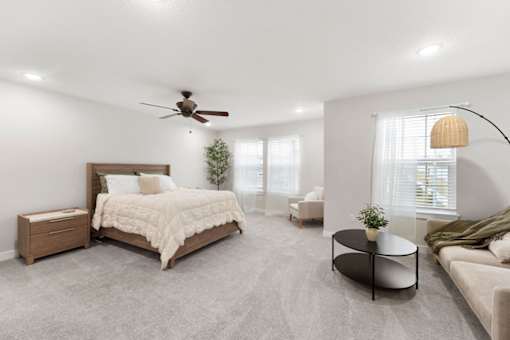 A bedroom with a large bed, a couch, and a ceiling fan.