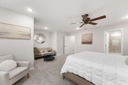 A bedroom with a large bed and a ceiling fan.