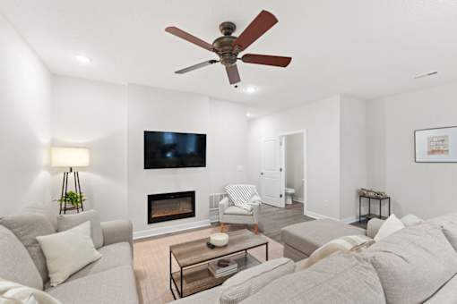 A living room with a grey couch, a fireplace, and a television mounted on the wall.