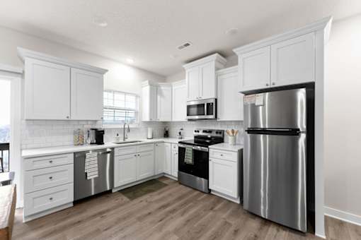 A modern kitchen with white cabinets and stainless steel appliances.