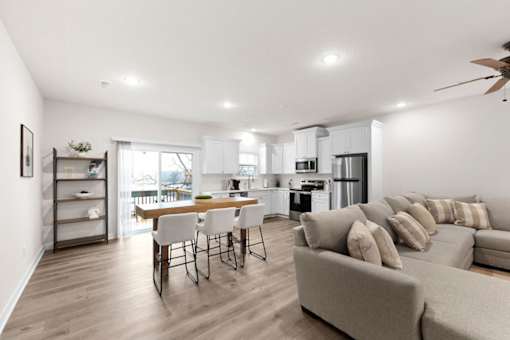 A modern living room with a dining area and kitchen in the background.