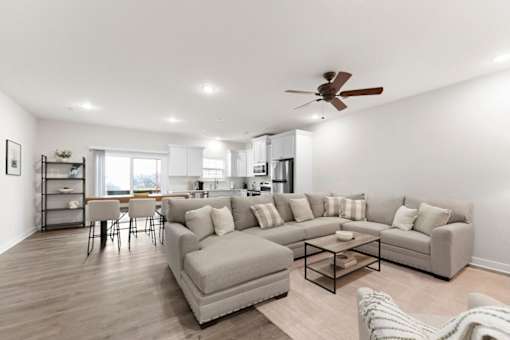 A living room with a grey couch, a coffee table, and a ceiling fan.
