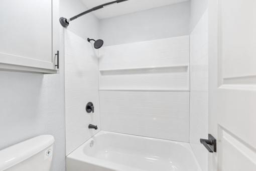 A white bathroom with a tub, shower, and towel rack.