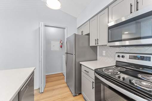 A modern kitchen with stainless steel appliances and white countertops.