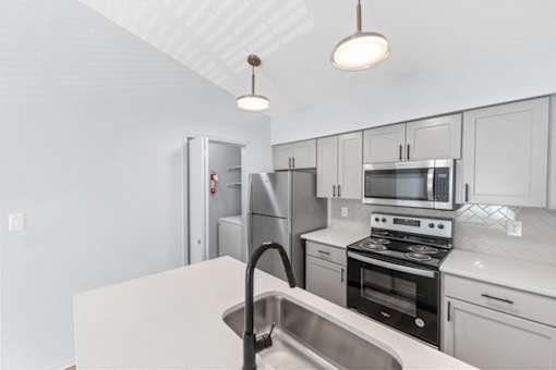 A kitchen with white cabinets and a stainless steel sink.