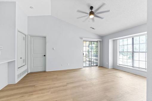 A room with a ceiling fan and wooden flooring.