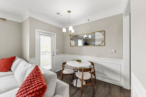 A living room with a white couch, a round table, and a mirror.