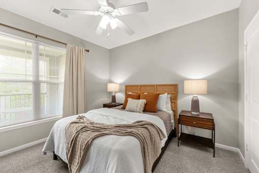 A bedroom with a bed, two lamps, and a ceiling fan.