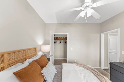 A bedroom with a bed, pillows, and a ceiling fan.