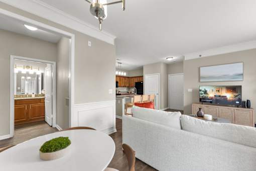 A living room with a white couch and a green plant on a white table.