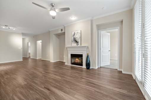 A spacious room with a fireplace and wood flooring.