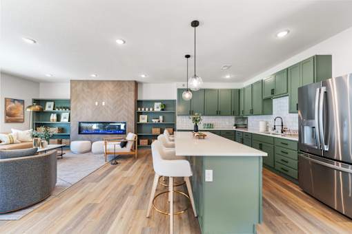 A modern kitchen with a white island and green cabinets.