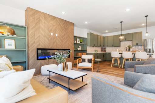 A modern living room with a large couch, a coffee table, and a TV mounted on the wall.