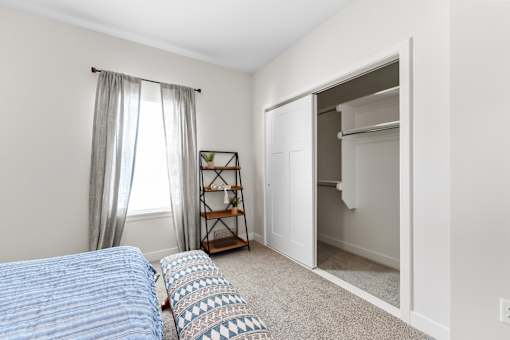 A bedroom with a bed, pillows, and a small shelf.