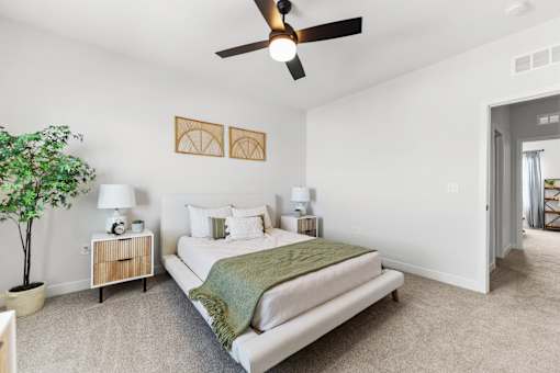 A bedroom with a bed, nightstand, and a ceiling fan.