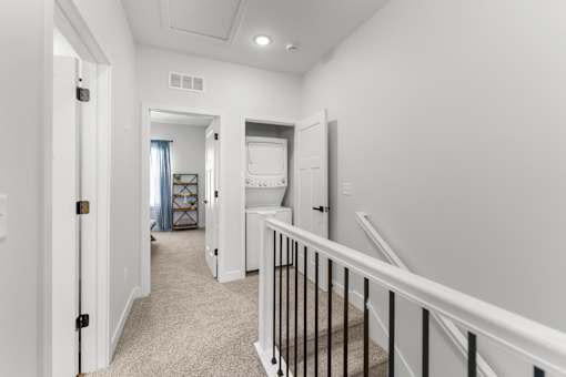 A hallway with a staircase and a white door.