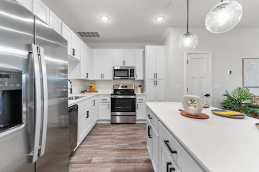 A modern kitchen with a refrigerator on the left and a stove top oven in the middle.