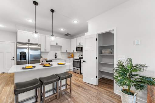 A kitchen with a white counter top and bar stools.