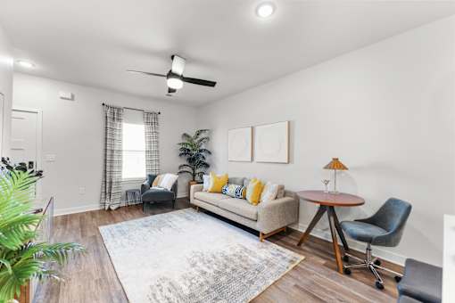 A living room with a couch, chair, and potted plant.