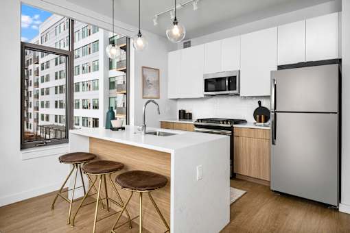 A modern kitchen with a white countertop and stainless steel appliances.