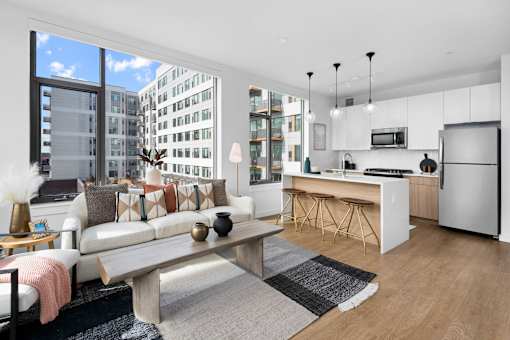 A modern living room with a large window and a kitchen area.