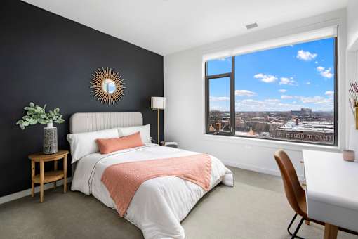 A bedroom with a large bed and a view of the city through the window.