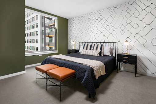 A bedroom with a bed, bench, and wall decoration.