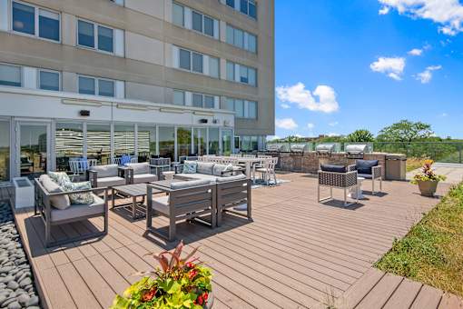 A wooden deck with chairs and tables is in front of a building.
