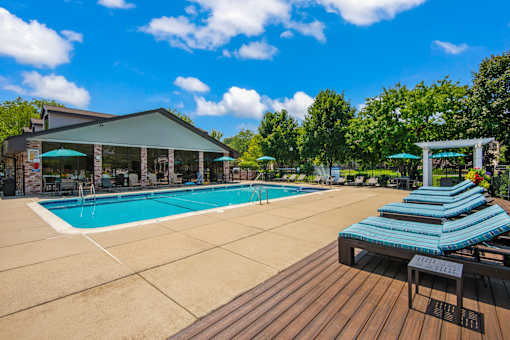 A pool with sun loungers and a building in the background.